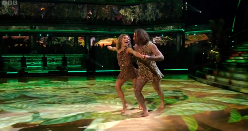 a man and a woman are dancing in front of a bbc logo