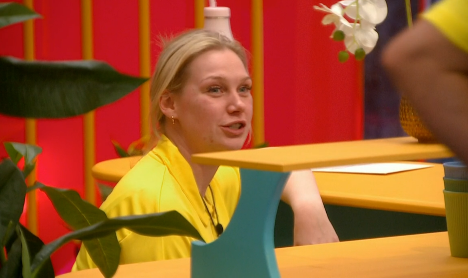 a woman in a yellow shirt sits at a table