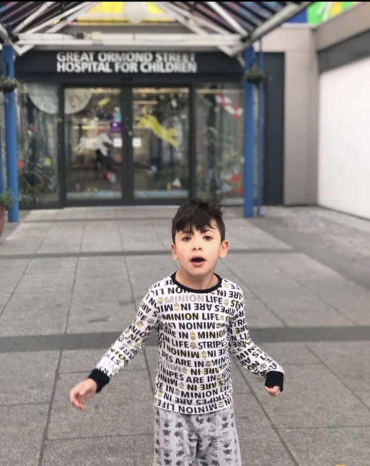 a young boy stands in front of the great ormond street hospital for children