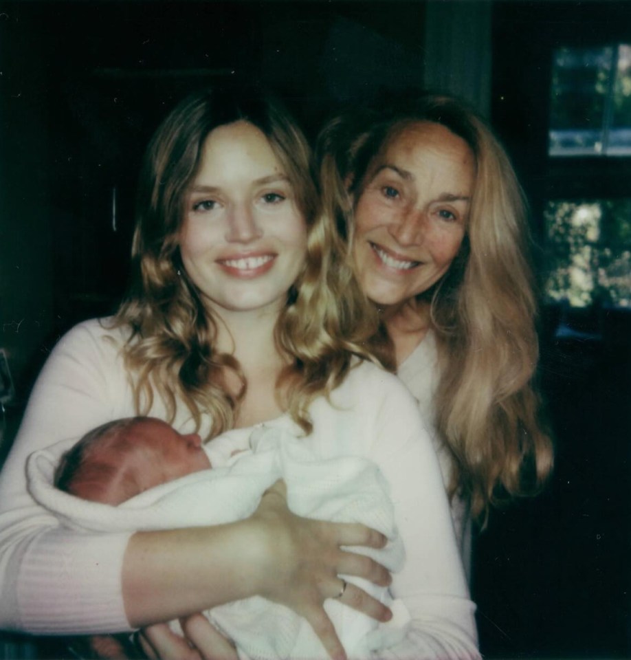 a woman holding a baby next to another woman