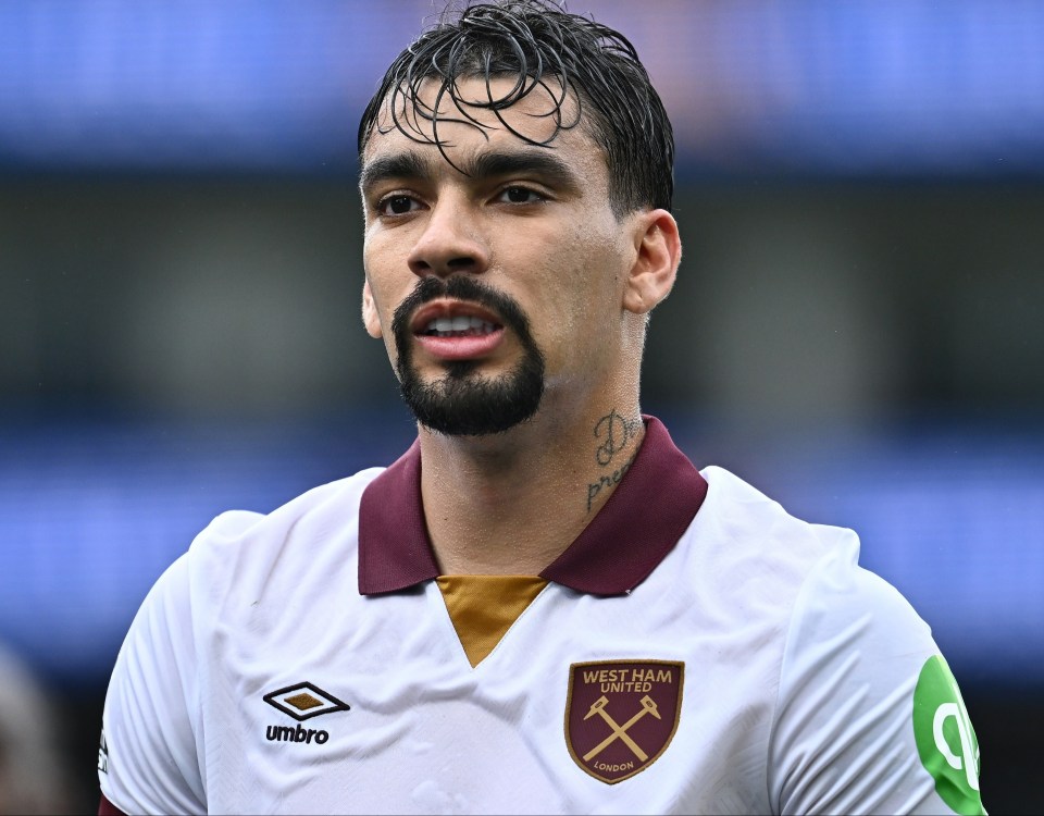 a man with a beard is wearing a west ham united jersey