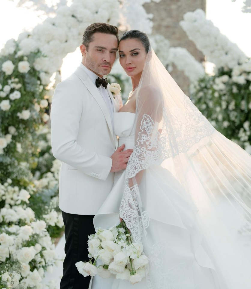 a bride and groom pose for a picture in front of white flowers