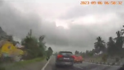 a car is driving down a highway on a cloudy day .