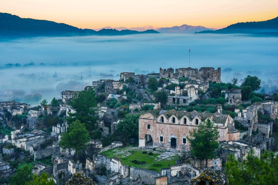 a castle in the middle of a valley with mountains in the background