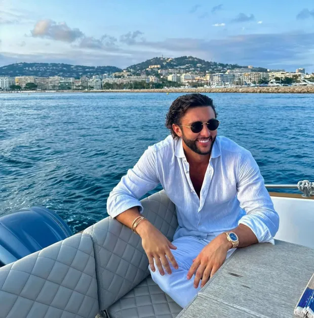 a man wearing sunglasses is sitting on a boat in the ocean