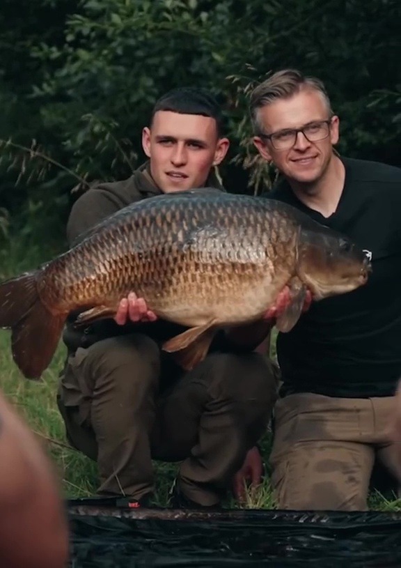 two men are holding a large carp in their hands