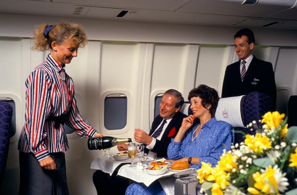 a flight attendant pours champagne into a woman 's glass