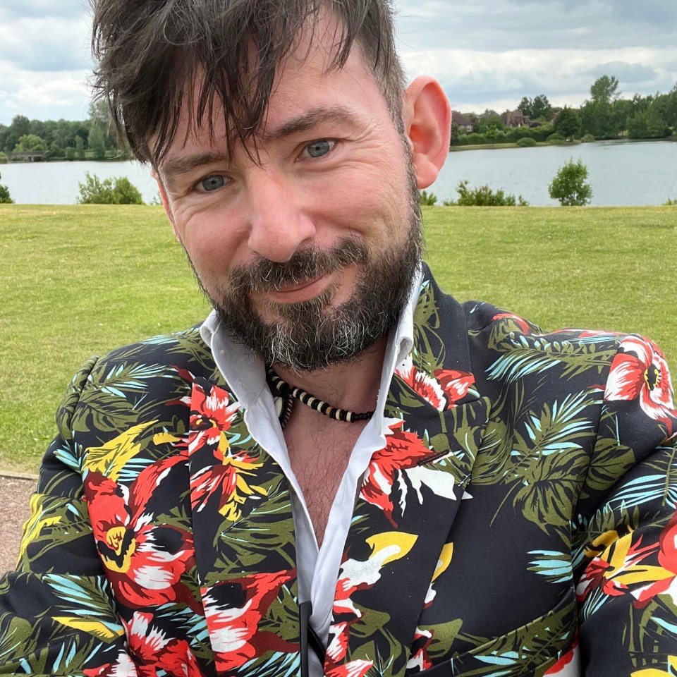 a man with a beard is wearing a floral jacket