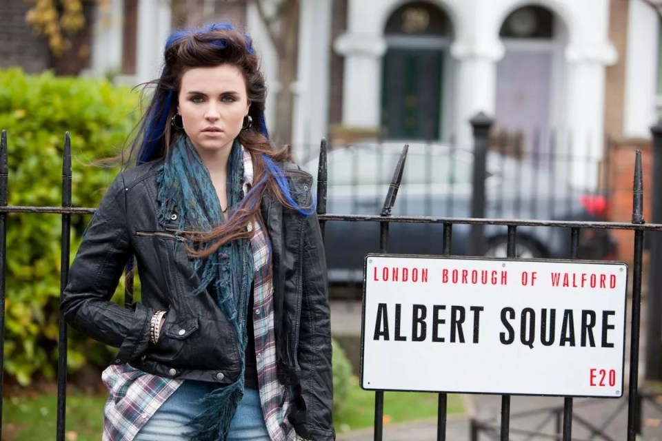 a woman stands in front of a sign for albert square