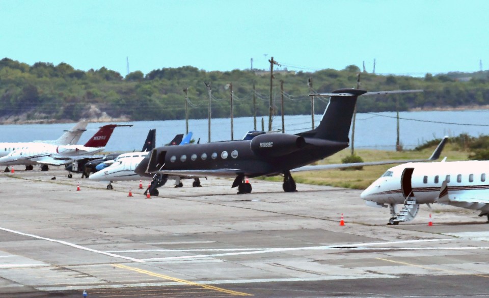 a black plane with the letters n932c on the tail sits on a runway