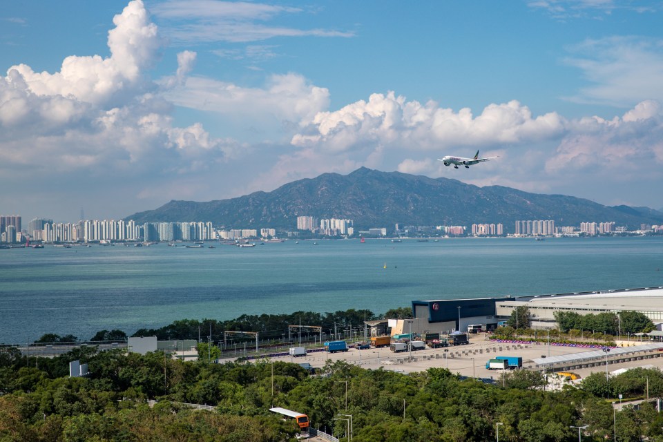 a plane flying over a body of water with mountains in the background