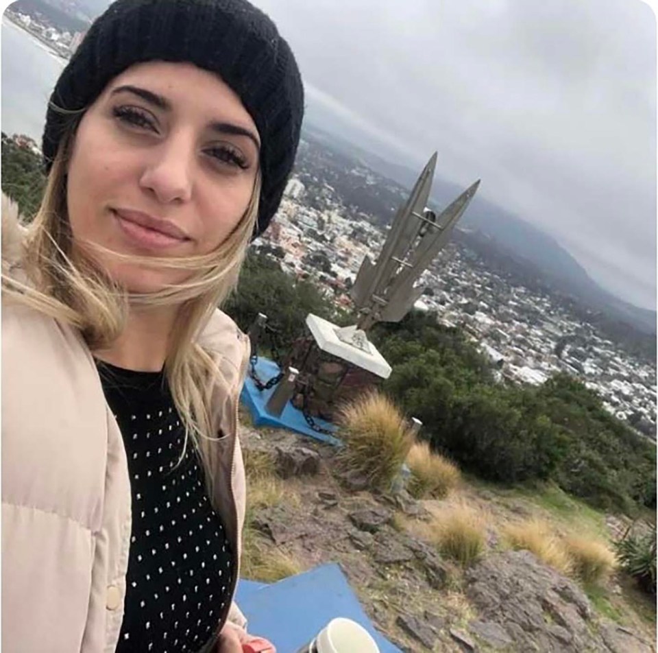 a woman standing on top of a hill with a city in the background