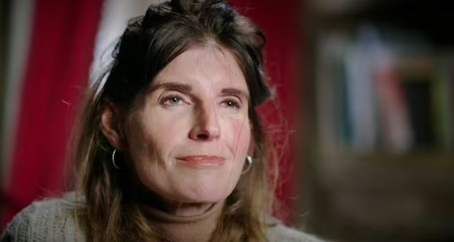 a close up of a woman 's face with a red curtain in the background .