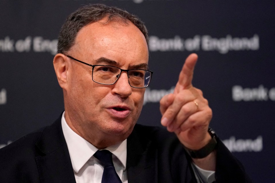 a man in a suit and tie points his finger at the bank of england