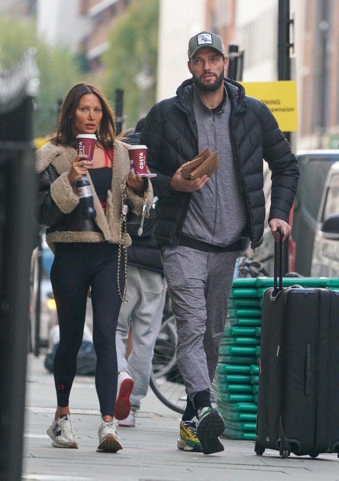 a man and woman walking down a street holding costa coffee cups