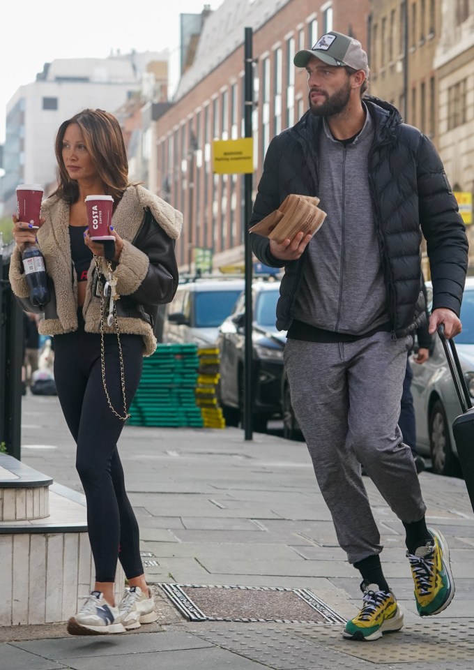 a man and a woman walking down a street holding costa coffee cups