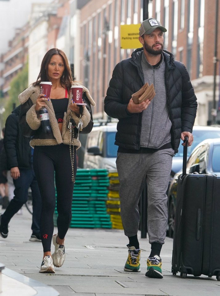 a man and a woman walking down a street holding costa coffee cups