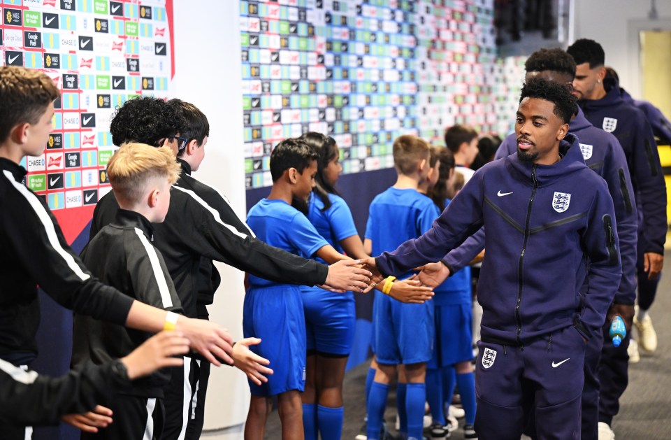 a man in a nike jacket shakes hands with a group of kids