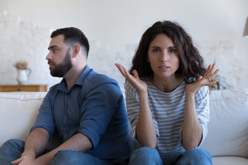 a man and a woman sit back to back on a couch