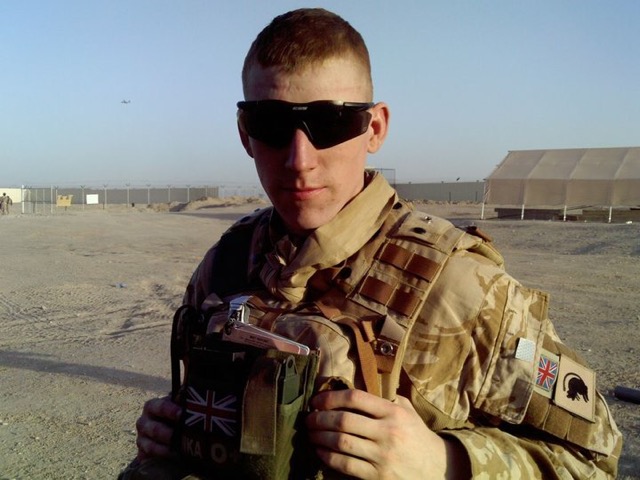 a man in a military uniform holds a flask with the british flag on it