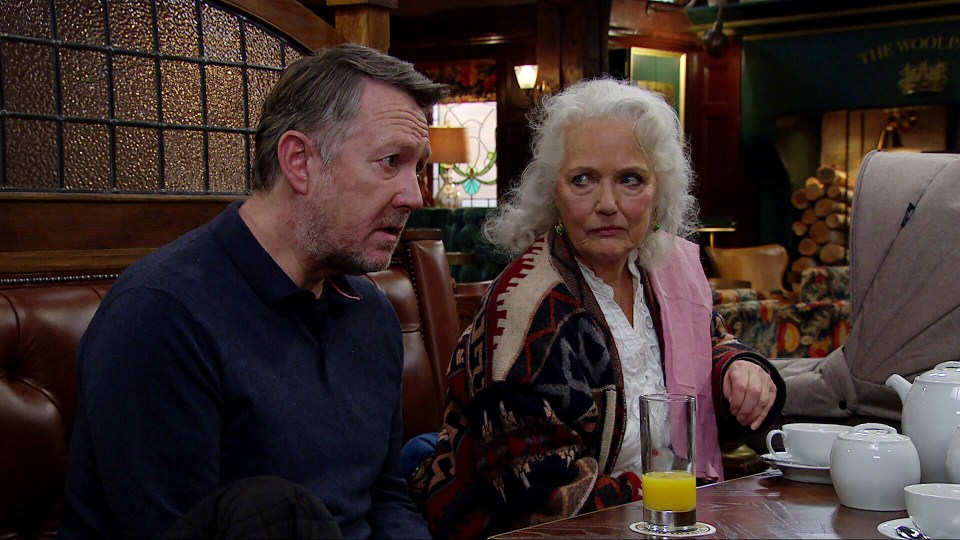 a man and woman sit at a table in front of a sign that says the wolf