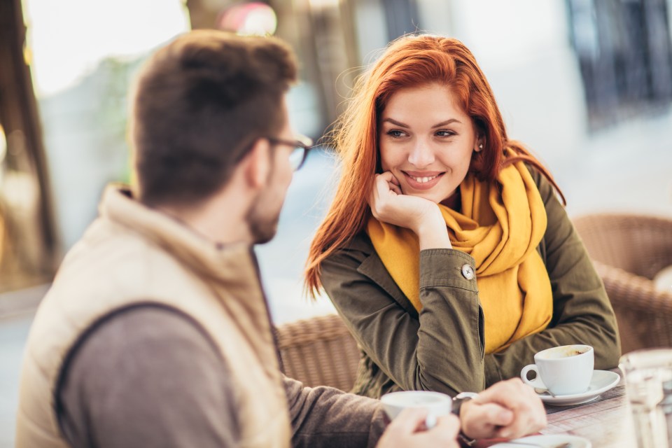 a man and a woman are sitting at a table with cups of coffee