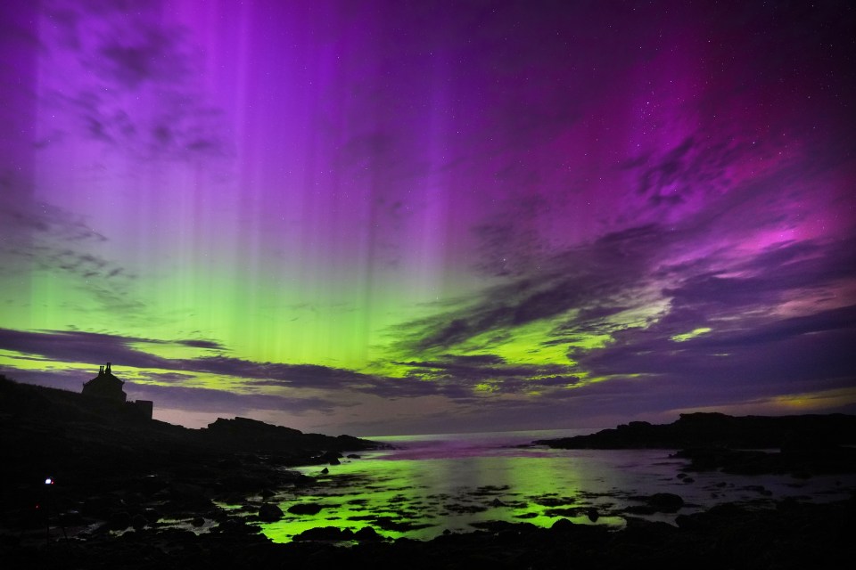 a purple and green sky over a body of water