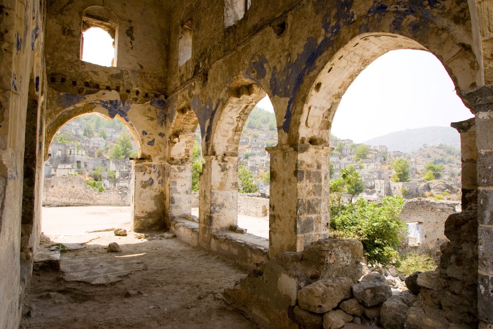 a very old building with arches and a mountain in the background