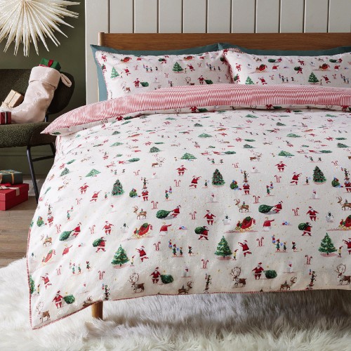 a bed with a duvet cover with santa clauses and christmas trees on it