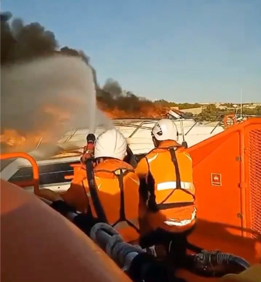 two men in orange vests are on a boat with smoke coming out of the back