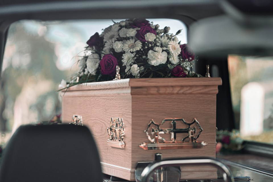 a coffin with flowers in it is in a car