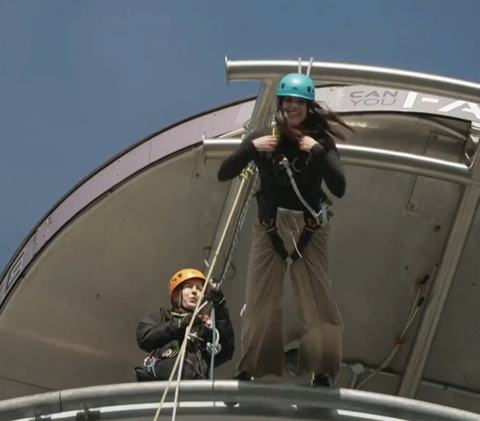 a woman in a blue helmet is standing in front of a sign that says " can you "