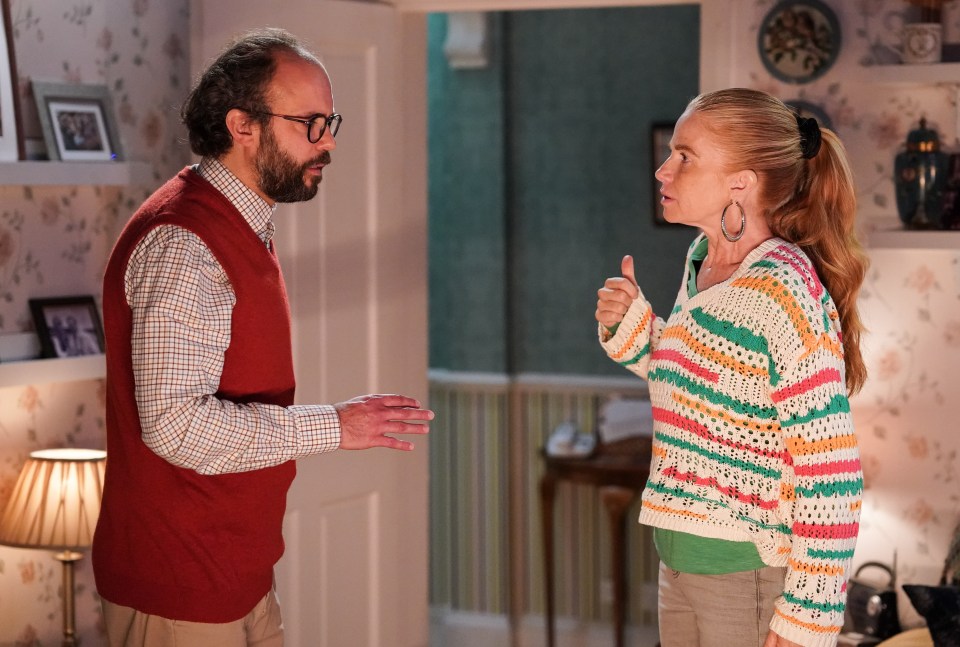 a man in a red vest is talking to a woman in a colorful sweater