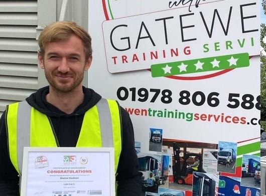 a man in a yellow vest is holding a certificate in front of a sign .