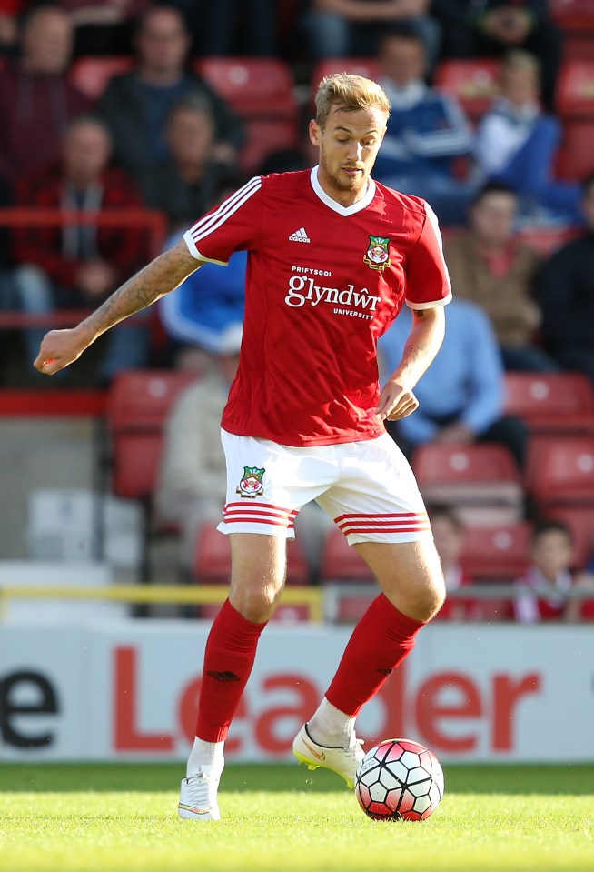 a soccer player in a red jersey with glyndŵr university on it