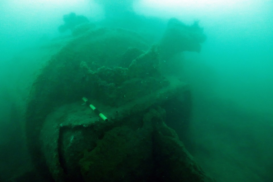 a scuba diver is swimming near a large rock in the water