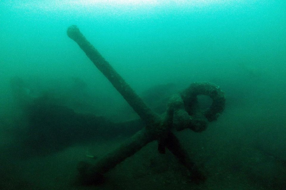 a large anchor in the water with a rope around it