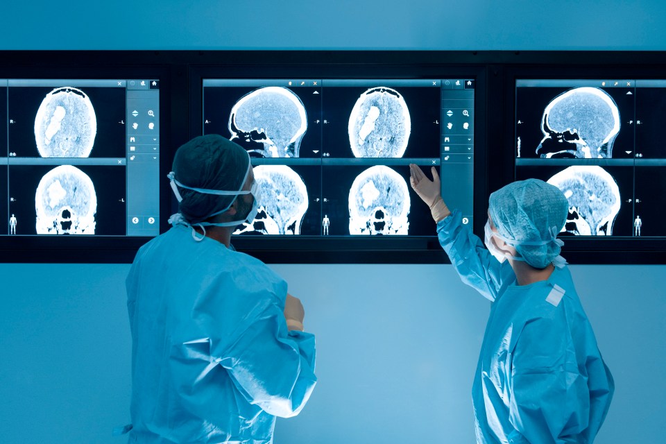 two surgeons are looking at images of a brain