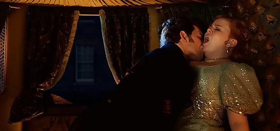 a man and woman are kissing in front of a window