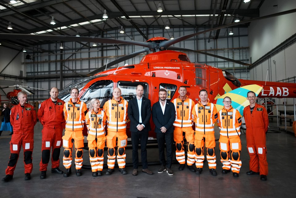 a group of people standing in front of a red london air ambulance