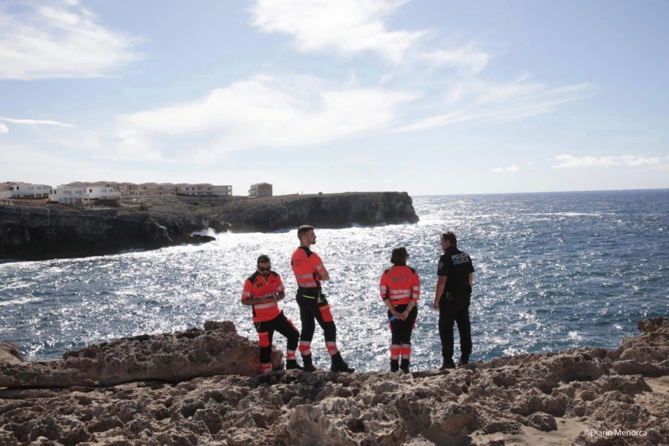 two police officers stand on a rocky cliff overlooking the ocean