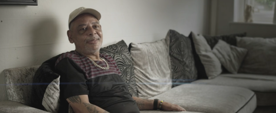 a man sitting on a couch with a tattoo on his arm that says ' i love you '