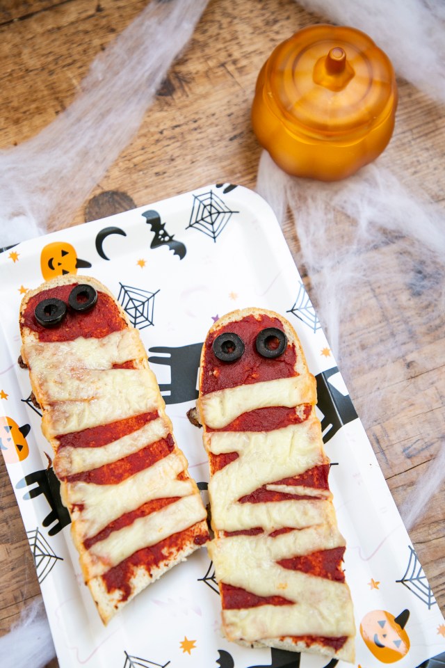 two mummy shaped pizzas are on a paper plate