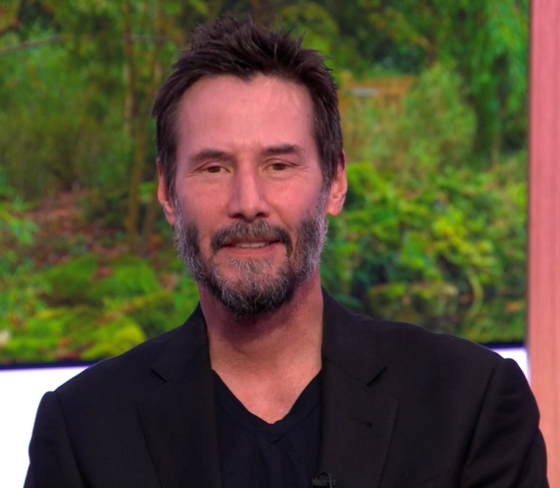 a man with a beard is smiling in front of a screen that says bbc