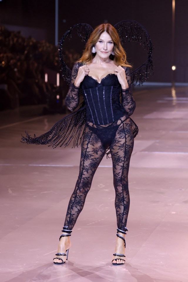 a woman in a black lace outfit is walking down a runway