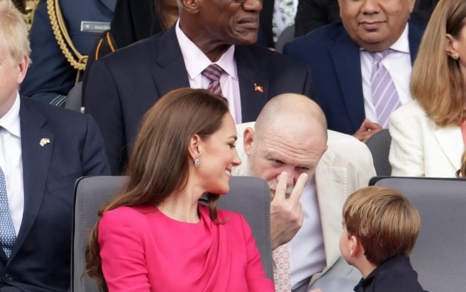 a man wipes his nose while sitting next to a woman in a pink dress