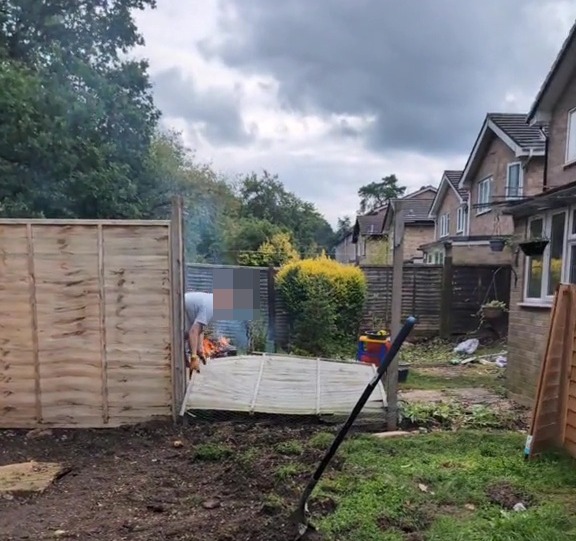 a backyard with a wooden fence and a shovel in the dirt