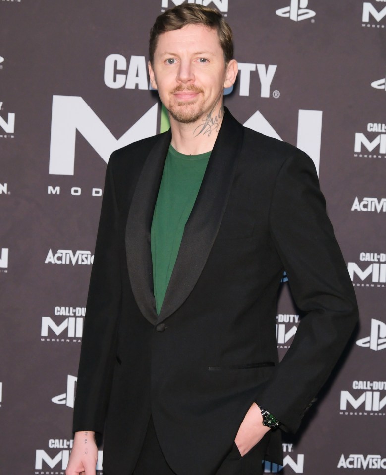 a man in a tuxedo stands in front of a call of duty sign