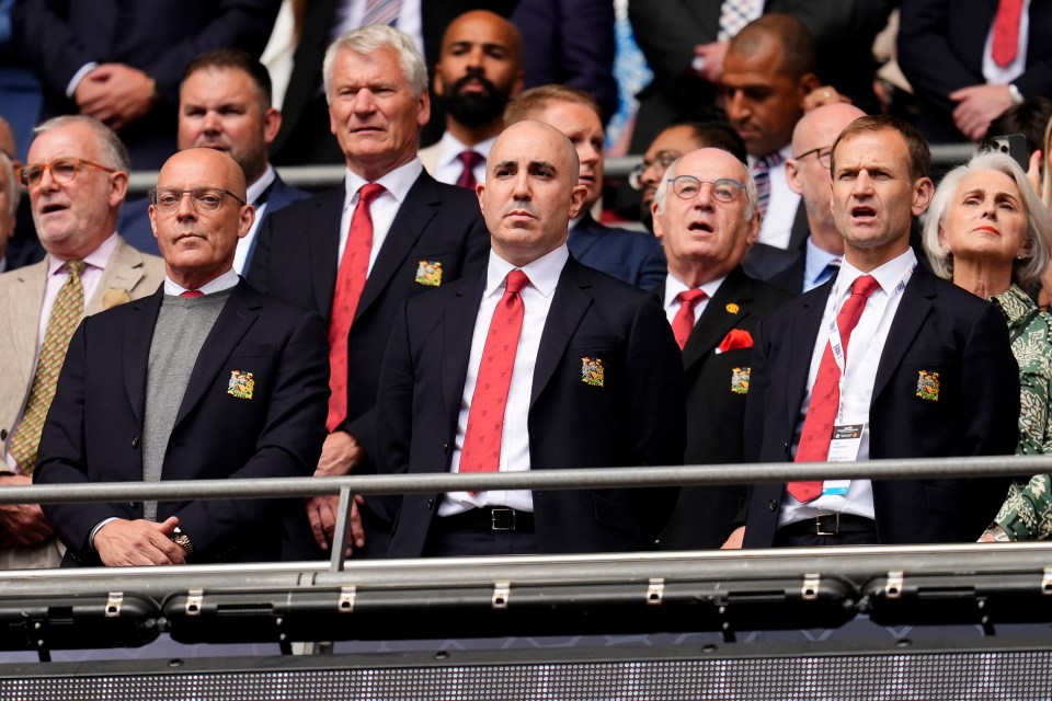 a group of men sitting in a stadium wearing suits and ties