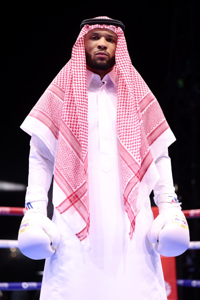 a man wearing a keffiyeh and boxing gloves stands in a boxing ring